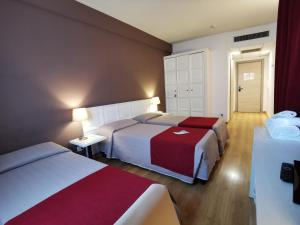 Habitación de hotel con 2 camas con sábanas rojas y blancas en Hotel President, en Prato