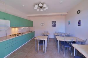 a kitchen with green cabinets and tables and chairs at Naytilus family Hotel in Kabardinka
