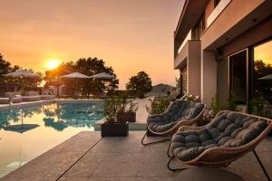 a pool with two lounge chairs next to a building at San Servolo Wellness Homes in Buje