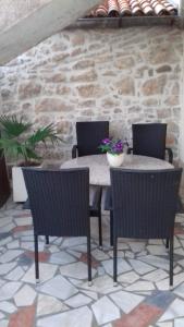 un patio con tavolo, sedie e parete in pietra di Apartment Magdic a Brzac
