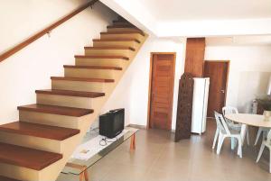 a room with a staircase with a tv and a table at Casa na praia em SC com Wi-Fi e churrasqueira in Pinheira