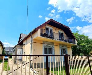 żółty dom z płotem przed nim w obiekcie Nap-Hold Apartman w mieście Keszthely