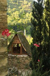 a small house with a roof in a garden at La Roquette-Chambre d'hôtes in Grand-Vabre