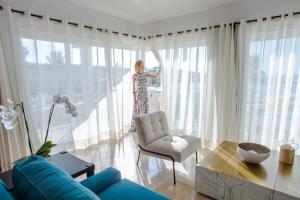 una mujer parada en una sala de estar mirando por la ventana en Corazón Cabo, a Noble House Resort, en Cabo San Lucas