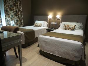 马德里Hotel Moderno Puerta del Sol的有两张床和一张书桌的酒店房间