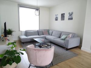 a living room with a couch and a pink chair at Vakantiewoning Mèzik in Maasmechelen