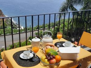 - une table avec des fruits et des jus de fruits sur un balcon dans l'établissement Zeza´s Sky, à Calheta