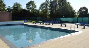 a large swimming pool with blue chairs and tables at "ZeeLandZon" Holiday home by the lake with Jacuzzi and Sauna in Herkingen