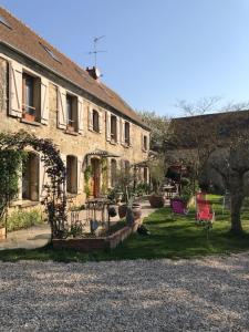 una casa grande con un patio con sillas delante en Chambre d hôtes en Montjavoult