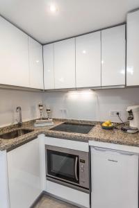 a kitchen with white cabinets and a microwave at Studio La Concha direkt am Meer in Torrox Costa