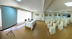 een kamer met witte tafels en stoelen en een scherm bij Hotel Vigo Plaza in Vigo