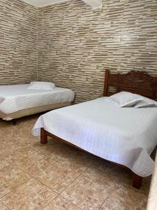 two beds in a bedroom with a brick wall at Pousada Cachoeira Dos Sonhos in Serra Negra +47 photos