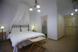 a bedroom with a large white bed and a chair at Mando Beachfront in Stafylos
