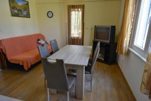 comedor con mesa, sillas y TV en Apartmani Zlata, en Supetarska Draga