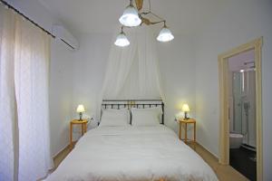 a bedroom with a white bed with two lamps on two tables at Mando Beachfront in Stafylos