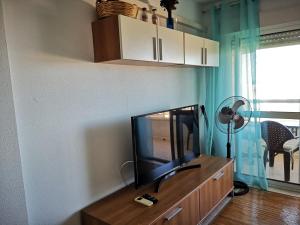 ein Wohnzimmer mit einem Flachbild-TV auf einem Holzschrank in der Unterkunft Alta Vista - apartamento con 2 dormitorios y vista al mar in Torrevieja