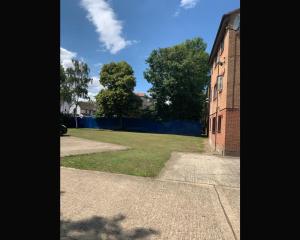 a building with a grassy yard next to a building at Stunning 1 bedroom apartment in Dagenham in Dagenham