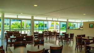 a restaurant with tables and chairs and windows at Paraíso na terra - Carneiros Beach Resort in Tamandaré