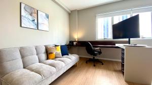 uma sala de estar com um sofá e uma secretária em QSA - Anora Spaces - Metropolis Alphaville em Barueri