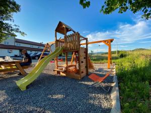 a playground with a slide and two chairs at Apartmani Fenestra in Otočac
