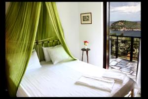 a bedroom with a bed with a green canopy at Mando Beachfront in Stafylos