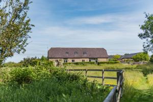 an old house in a field with a fence at Owl Barn in Aston