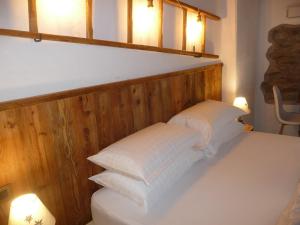 a pile of white pillows on a bed with two lights at BeB LUCA76 in Avise