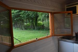 a window in a kitchen with a view of a yard at Roulotte paisible au milieu de la nature in Sainte-Eulalie-en-Born
