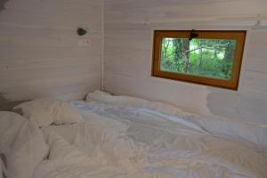 an unmade bed in a room with a window at Roulotte paisible au milieu de la nature in Sainte-Eulalie-en-Born +2 photos