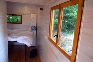 een kleine slaapkamer in een tiny house met een raam bij Roulotte paisible au milieu de la nature in Sainte-Eulalie-en-Born