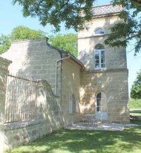 um antigo edifício de pedra com um banco no quintal em La Tour du Domaine de Choisy em Abzac