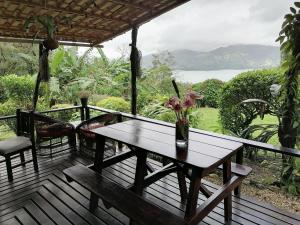 um deque de madeira com uma mesa com flores em La Ceiba Tree Lodge em Tilarán