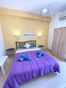 ein großes lila Bett mit zwei blauen Kissen darauf in der Unterkunft Avra Budget Beach Rooms in Benitses