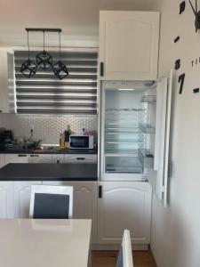  La cuisine est équipée de placards blancs et d'un réfrigérateur. dans l'établissement Royal Residence Apartmani 2, à Pančevo