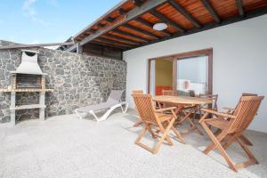patio ze stołem i krzesłami oraz kamienną ścianą w obiekcie Villa 1B w mieście Playa Blanca