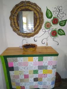 a mirror and a table with a quilt on a wall at Pousada São Miguel Filosofal in São Miguel do Gostoso