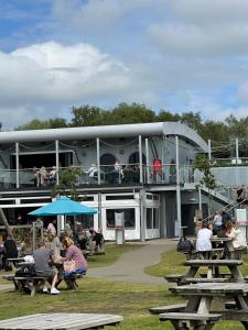 a group of people sitting at picnic tables in front of a building at Sunscape breaks At Tattershall Lakes in Tattershall