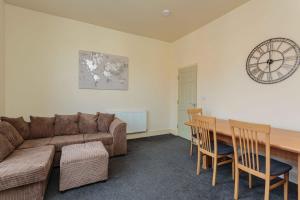 sala de estar con sofá, mesa y reloj en Cherry Property - Coconut Suite en Blackpool