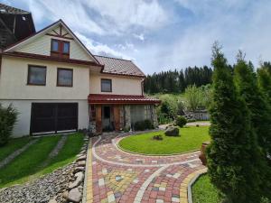a house with a brick walkway in the yard at Під горою in Volovets