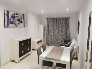 Sala de estar blanca con mesa y silla en Apartamentos el rebalaje, en Roquetas de Mar
