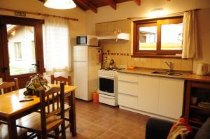 a kitchen with a table and a stove and a refrigerator at La Aljaba in El Bolsón