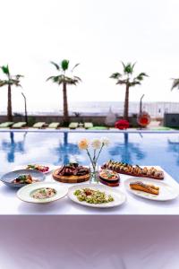 a table topped with plates of food next to a pool at Pinea Hotel Resort & Spa in Golem