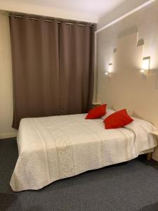 a bedroom with a bed with two red pillows at Hotel Chiffre in Albi
