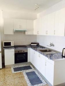 プラヤ・デ・サン・ファンにあるHola Apartments 14-3のキッチン(白いキャビネット、シンク、コンロ付)