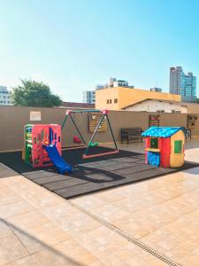 a play area with a swing and a playground at APÊ COM PISCINA E AR - 2Q DA PRAIA DA ENSEADA. in Guarujá