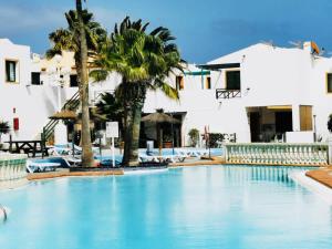 una piscina con palmeras y edificios blancos en Puerta del Sol (Caleta de Fuste), en Caleta de Fuste