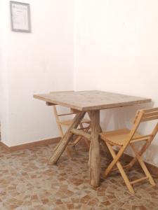 una mesa de madera y 2 sillas junto a una pared en CASA DELLE GUARDIE b&b, en Madonna di Fornelli