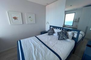 een slaapkamer met een bed met kussens en een raam bij Blue Infinity, Aquamarine apartment in Funchal