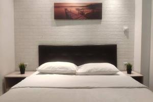 ein weißes Bett mit zwei Kissen und einer Ziegelwand in der Unterkunft Deluxe Apartment by Prima Lodging in Thessaloniki