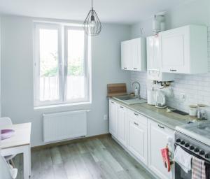 a white kitchen with white cabinets and a window at Apartament u Basi in Gdańsk